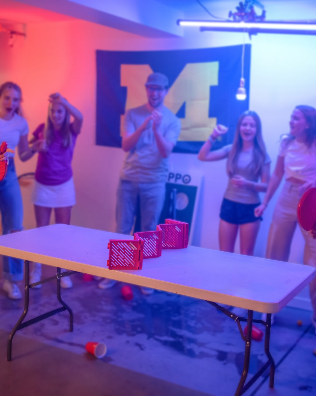A group erupting in celebration around a Pepper Pong table